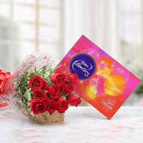 Bouquet of red roses with festive Cadbury chocolate gift box on a table, perfect for gifting.