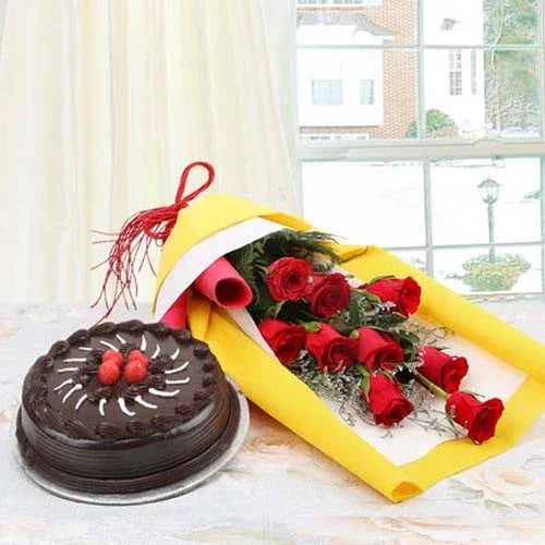 Bouquet of red roses and chocolate cake on table near bright window