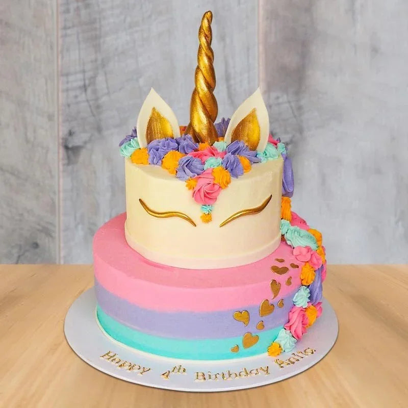 Unicorn-themed birthday cake with colorful frosting and gold accents on a wooden table.