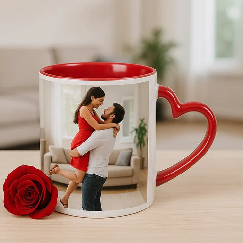 Mug with a heart-shaped handle featuring a printed image of a couple, placed on a surface with a red rose.