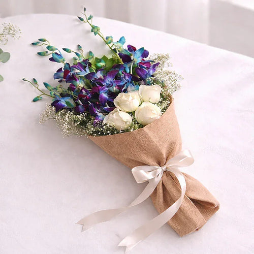 Bouquet of flowers wrapped in brown paper with a white ribbon on a light background