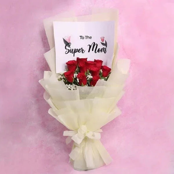 Bouquet of red roses with a card reading 'To The Super Mom' on a pink background