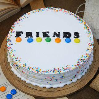 Cake with 'FRIENDS' text and colorful sprinkles on a wooden table.