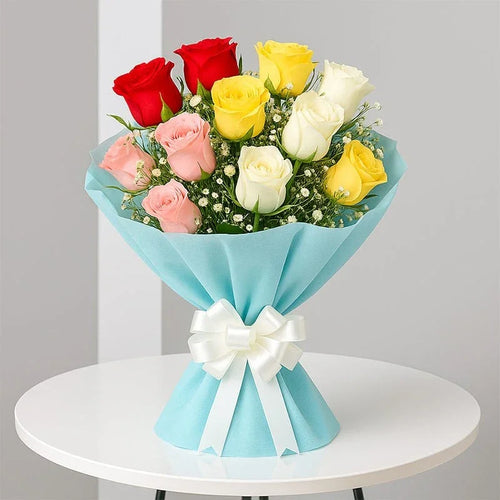 Bouquet of red, yellow, and white roses wrapped in blue paper with a white bow on a white table.