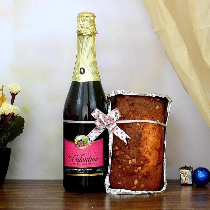 Bottle of Valentine sparkling wine with a loaf of bread in tinfoil packaging on a wooden surface.