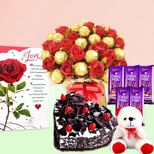 Bouquet of red roses and gold Ferrero Rocher chocolates with a black forest cake, teddy bear, and Cadbury Dairy Milk Silk chocolate bars 