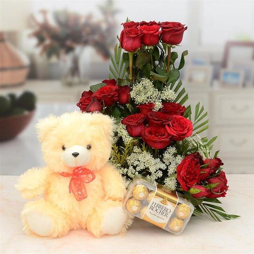 Bouquet of red roses, teddy bear, and chocolates on a table