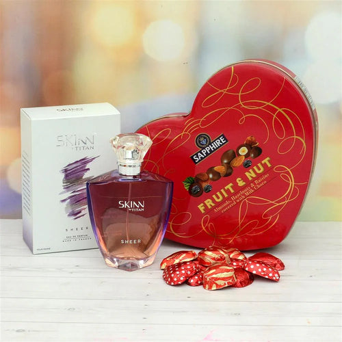 Skinn perfume bottle with a box and a heart-shaped Sapphire Fruit & Nut chocolate tin on a blurred background.