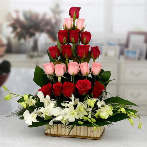 Three-tiered flower arrangement with red and pink roses and white orchids