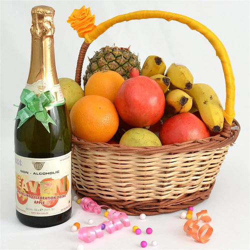Bottle of non-alcoholic sparkling apple cider next to a fruit basket on a white background