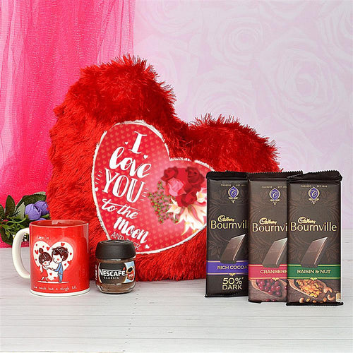 Red plush heart with 'I love you to the moon' text, coffee mug, Nescafe jar, and Cadbury Bournville chocolate bars on a white surface.