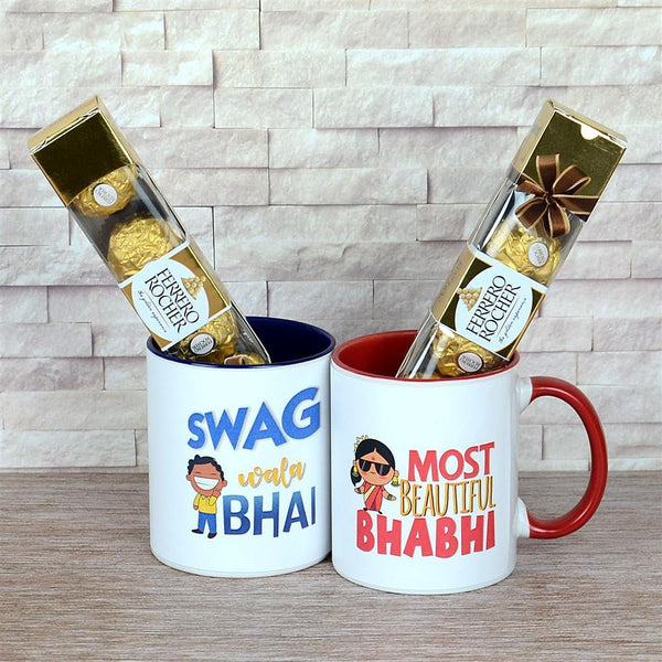 Two mugs with printed text and Ferrero Rocher chocolates on a wooden surface.