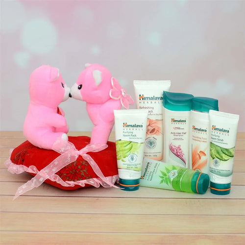 Two pink teddy bears kissing on a red heart with Himalaya skincare products