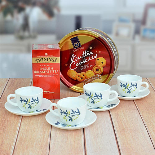 Tea set with Twinings tea box and a tin of cookies on a wooden table.