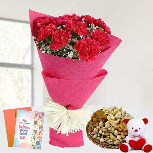 Bouquet of red flowers wrapped in pink paper with a card, bowl of Dry Fruits , and teddy bear on a white background