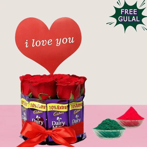 Dairy Milk chocolate bar arrangement with red roses and a heart-shaped 'I love you' sign, accompanied by free gulal on a light pink background.