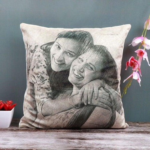 Decorative pillow with a printed photo of two people hugging on a wooden surface with flowers.