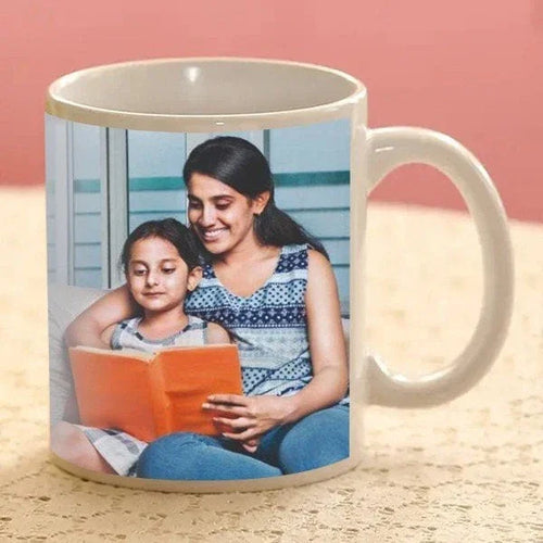Mug with a printed photo of a woman and child reading a book on a wooden surface.