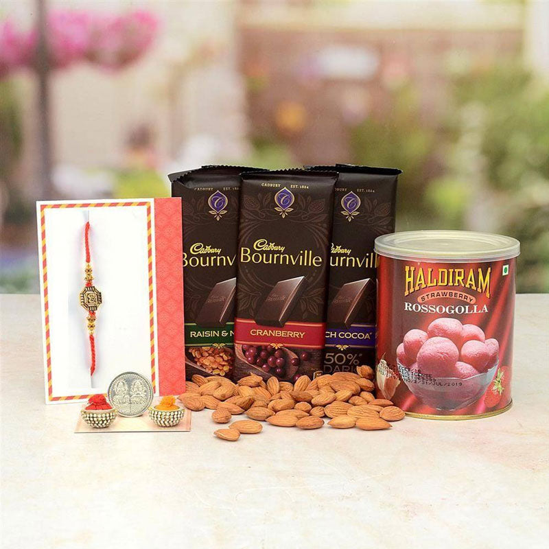 Cadbury Bournville chocolate bars, a can of Haldiram Rosogolla, and almonds on a table with a blurred outdoor background.