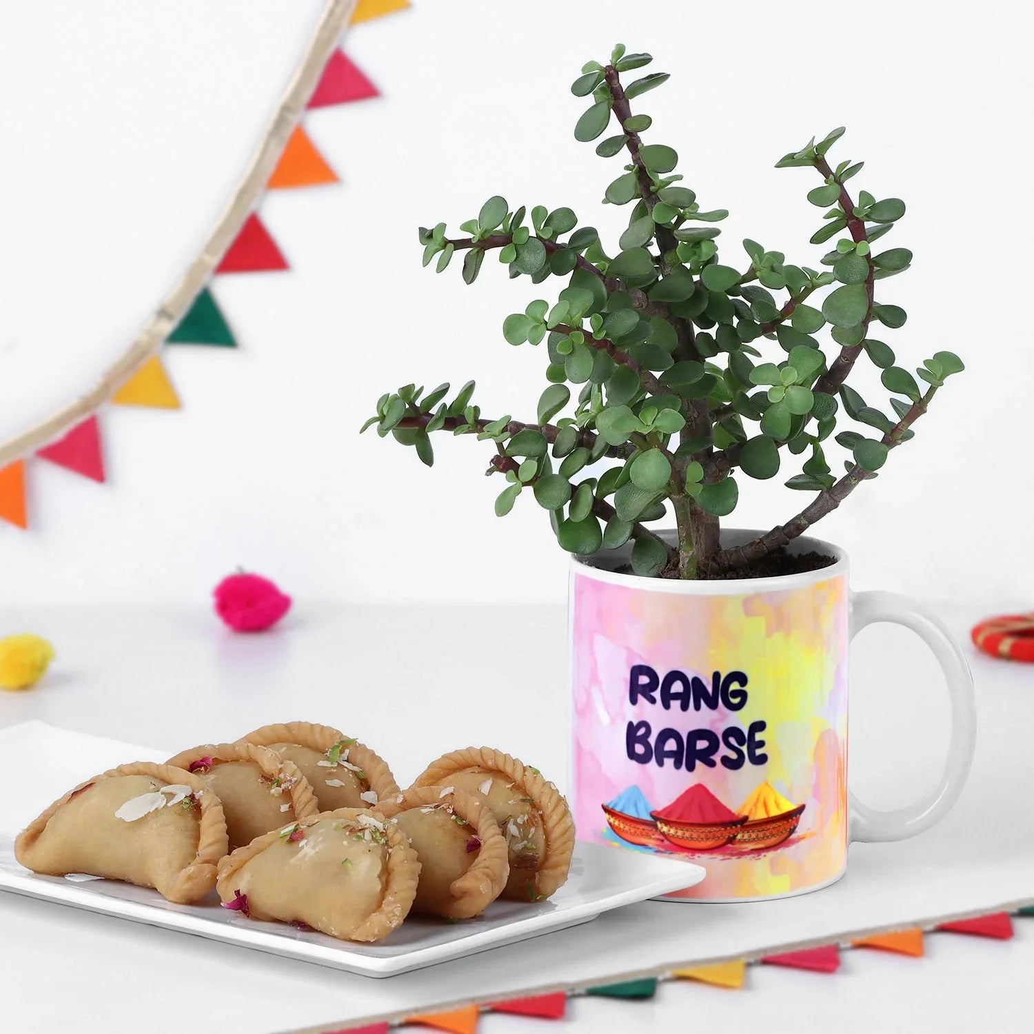 Mug with 'Rang Barse' design, plant, and snacks on a decorative background