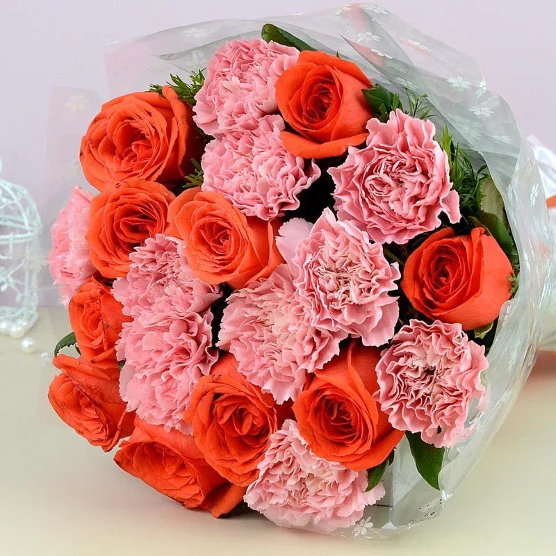 Bouquet of pink and orange flowers in clear plastic wrap on a light background