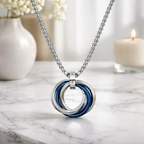 Necklace with a blue and silver pendant on a marble surface with a blurred background