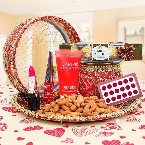 Karwachauth Pooja Thali with snacks, makeup, and chocolates on a heart-patterned tablecloth.
