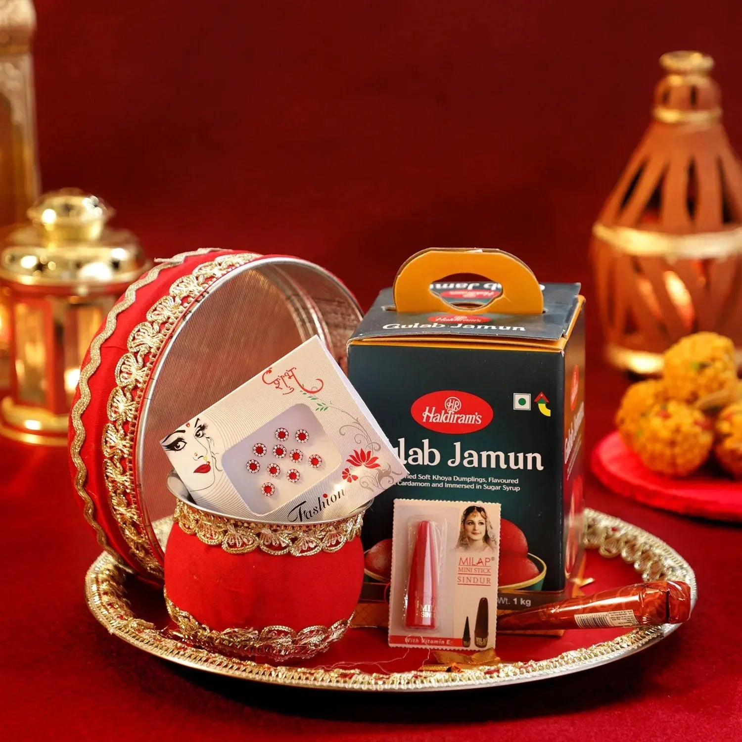 Decorative tray with a red container, card, and other items 
