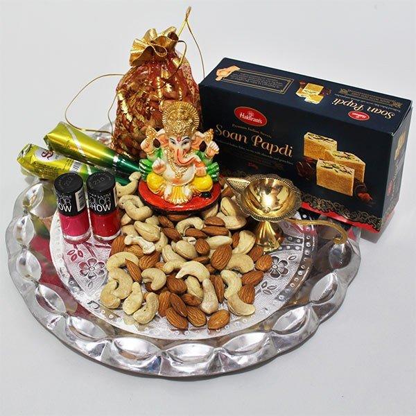 Ganesh idol with snacks and candies on a tray, featuring Haldiram's soan papdi box.