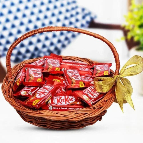 Basket of KitKat chocolate bars with a gold ribbon on a white background