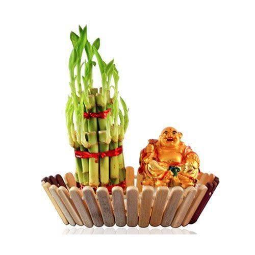 Decorative setup with green bamboo shoots and a small Buddha figurine on a white background