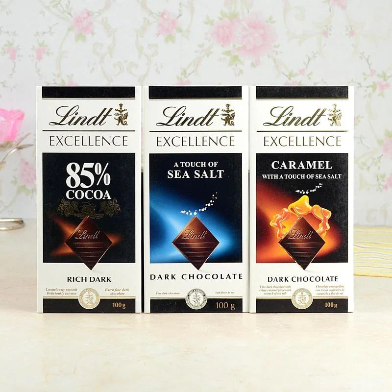 Three Lindt Excellence chocolate bars with different flavors on a light background.