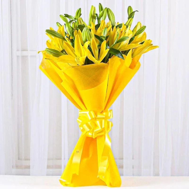 Bouquet of yellow flowers wrapped in yellow paper with a bow on a white background