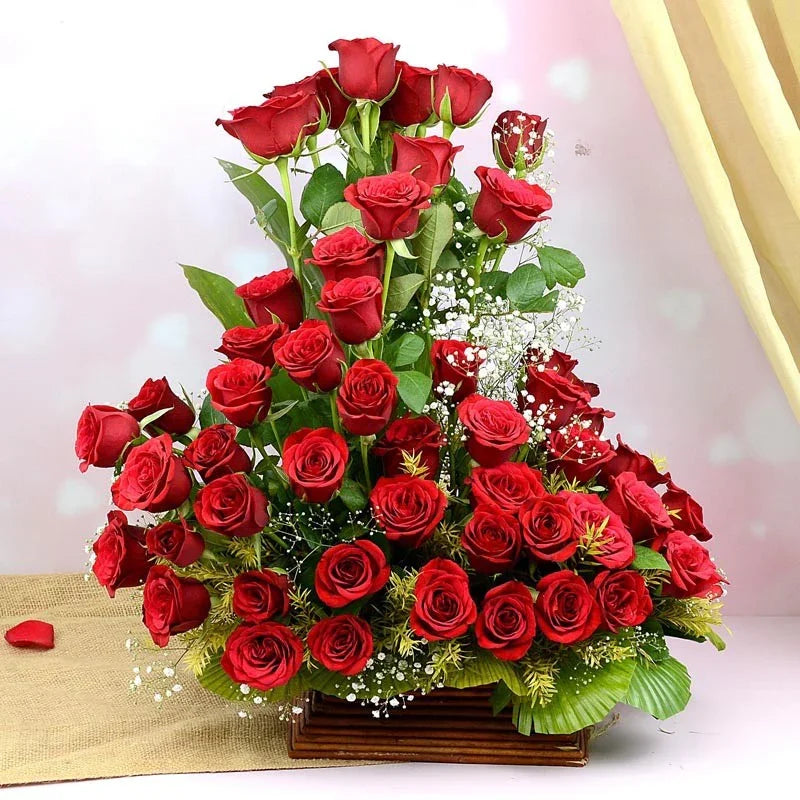 Bouquet of red roses with green leaves on a light pink background