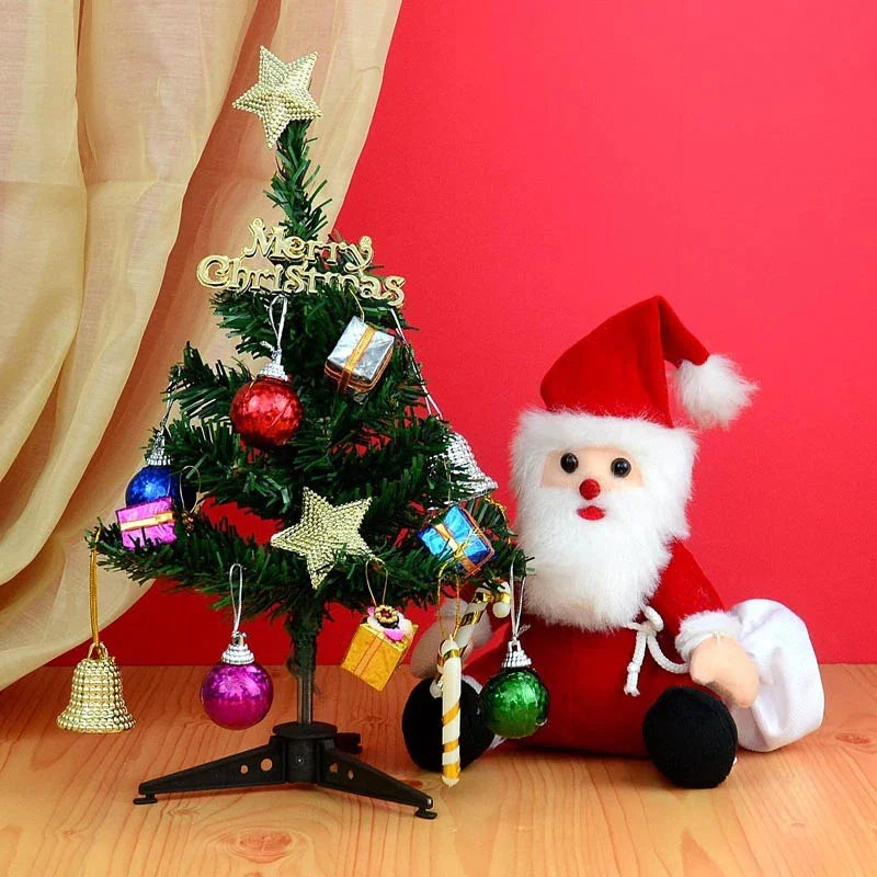 Small decorated Christmas tree with ornaments and a Santa Claus figure against a red background.