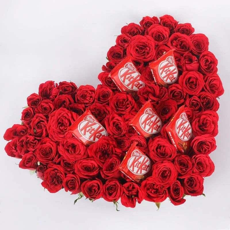 Heart-shaped arrangement of red roses with KitKat chocolate bars on a white background