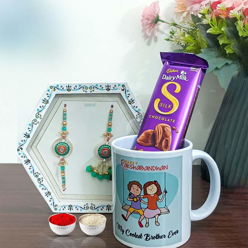 Mug with 'My Coolest Brother Ever' text, Cadbury Dairy Milk Silk chocolate, and rakhi set on a table.
