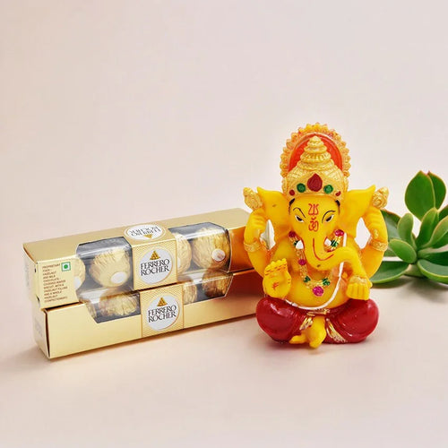 Small statue of a deity next to a box of Ferrero Rocher chocolates on a light background