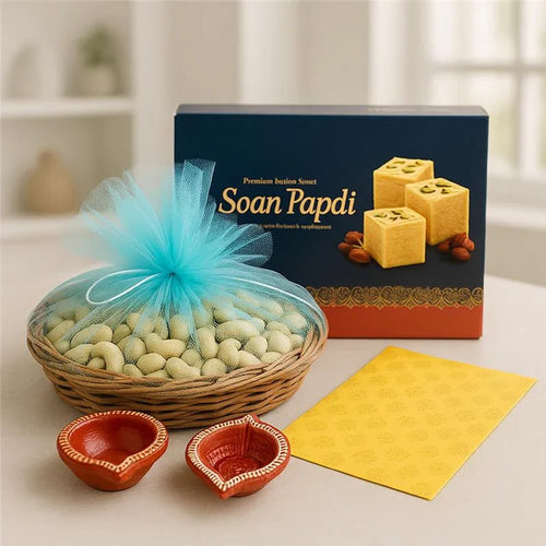 Diwali gift set with soan papdi box, basket of cashews, diyas and festive greeting card.