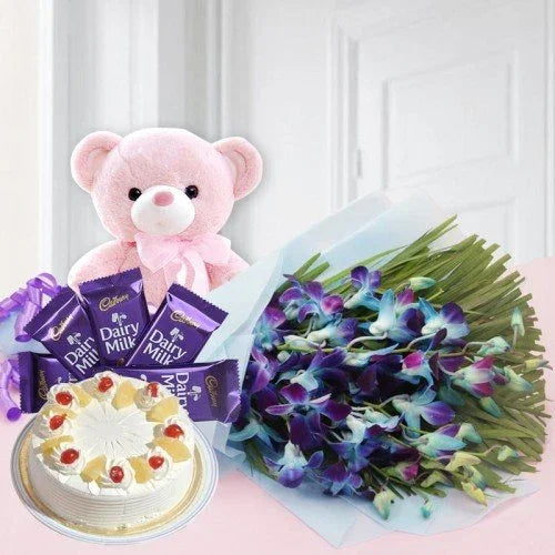 Gift set with pink teddy bear, bouquet of orchids, chocolate bars, and a fruit-topped cake