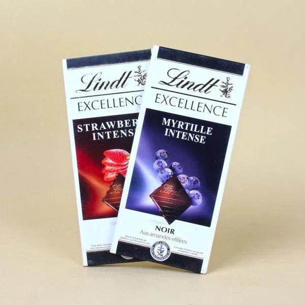 Two Lindt Excellence chocolate bars, strawberry and blueberry flavors, on a beige background.