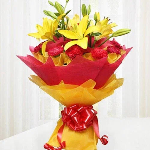 Bouquet of yellow lilies and red carnations wrapped in red and yellow paper with ribbon