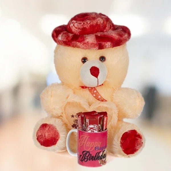 Plush teddy bear with red accents holding a Happy Birthday mug filled with chocolates