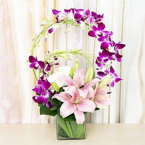 Fresh orchid and lily flower arrangement in a glass vase, elegant floral gift display