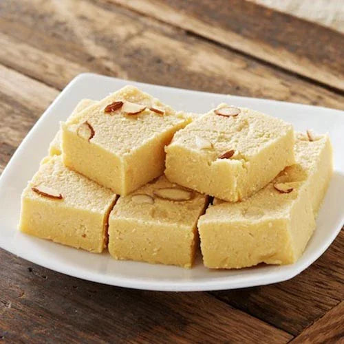 Plate of square pieces of Indian milk barfi garnished with sliced almonds