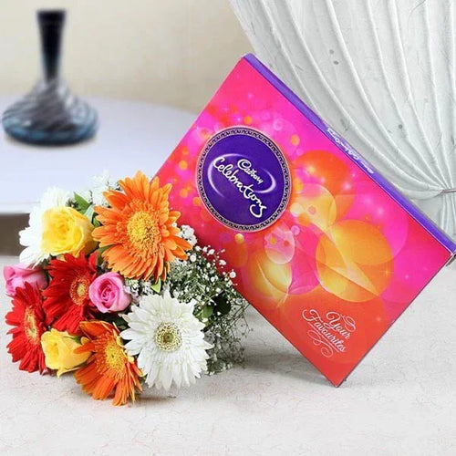 Cadbury Celebrations chocolate box with a bouquet of flowers on a table.