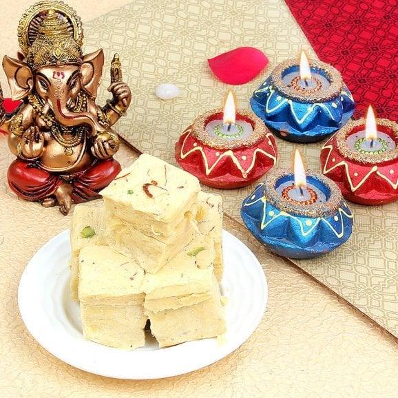 Indian festival gift set with sweets, decorative diyas, and a Ganesh idol on a festive background
