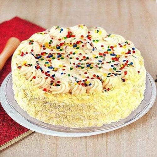 Decorative cake with white frosting and colorful sprinkles on a wooden surface.