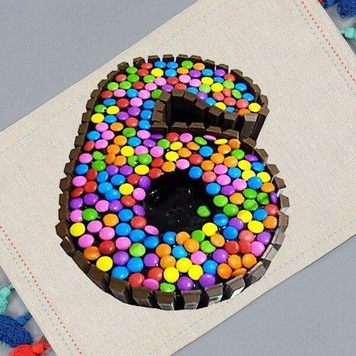 Colorful kit katli-coated number 6 on a textured surface