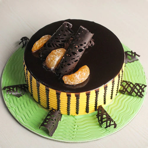 Cake decorated like a bee with black honeycomb, yellow body, and orange accents on a green base.